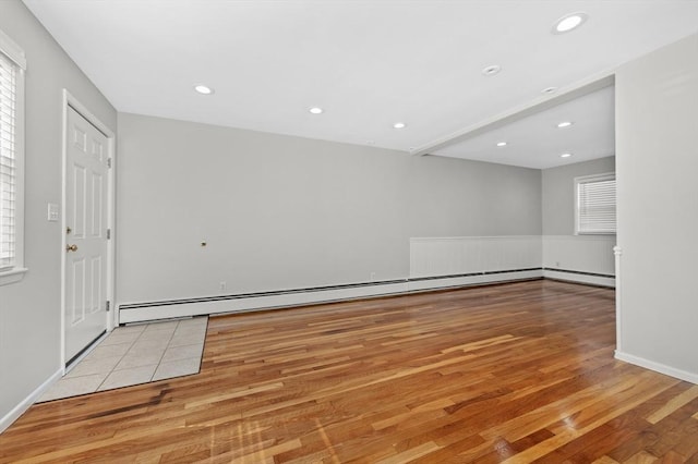 empty room with a baseboard radiator and light hardwood / wood-style flooring