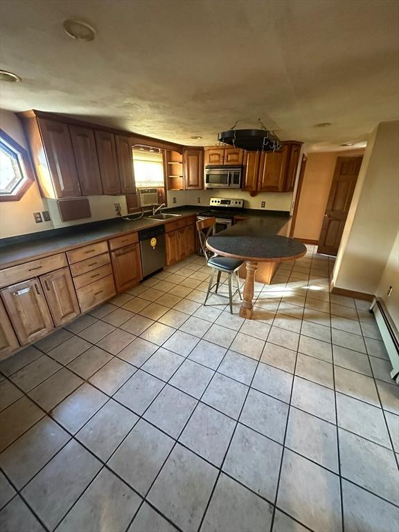 kitchen featuring dark countertops, brown cabinets, a breakfast bar, stainless steel appliances, and light tile patterned flooring