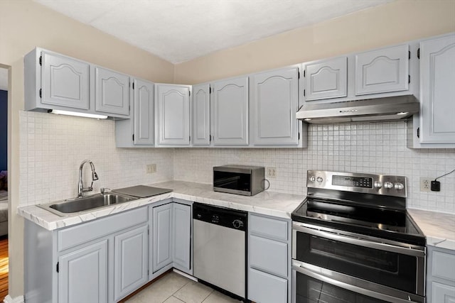 kitchen with stainless steel appliances, decorative backsplash, sink, gray cabinets, and light tile patterned floors