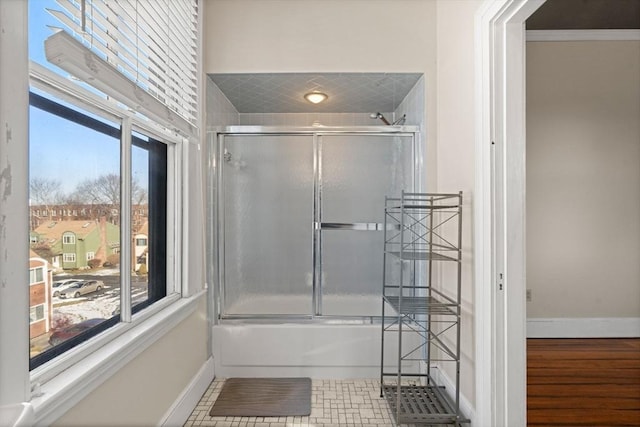 bathroom with bath / shower combo with glass door and plenty of natural light