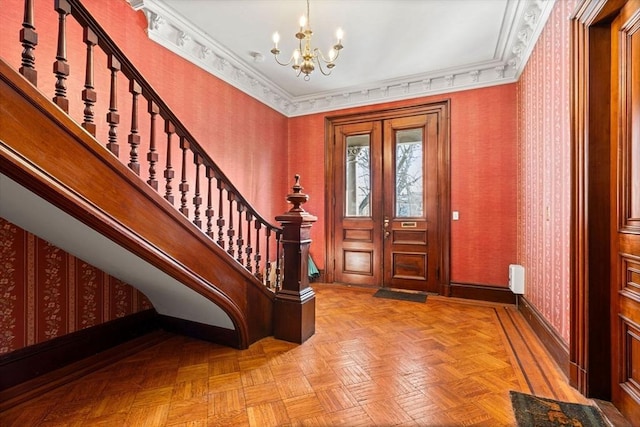 foyer entrance featuring french doors, light parquet flooring, a notable chandelier, and ornamental molding