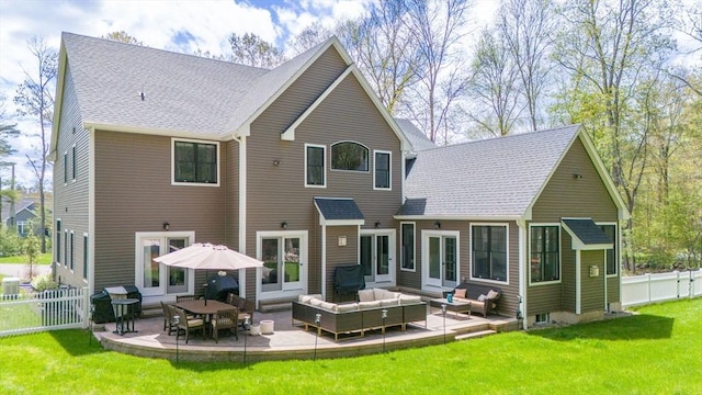 rear view of property with a shingled roof, a lawn, a patio, fence, and an outdoor living space