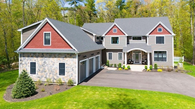 craftsman inspired home with stone siding, a shingled roof, a front lawn, and aphalt driveway