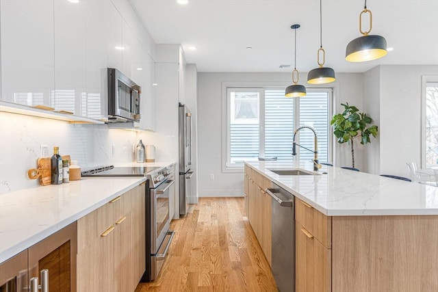 kitchen with white cabinetry, sink, stainless steel appliances, light hardwood / wood-style flooring, and decorative light fixtures