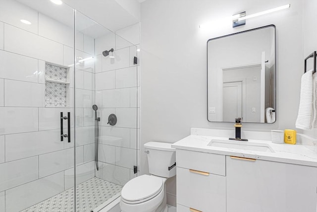 bathroom featuring vanity, a shower with shower door, and toilet