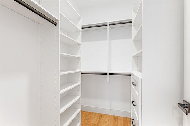 walk in closet with light hardwood / wood-style floors