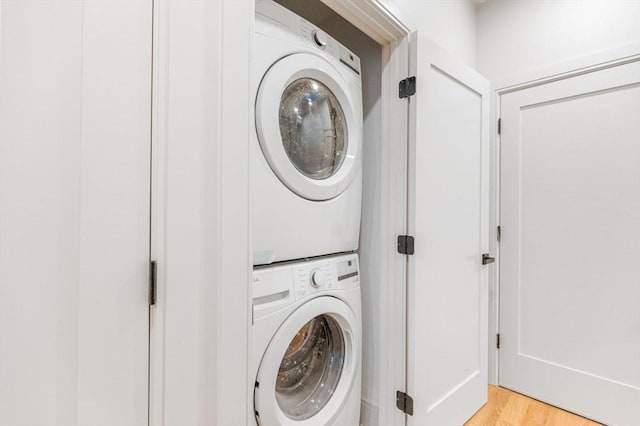 laundry area with stacked washing maching and dryer and light wood-type flooring