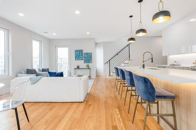 living room with a wealth of natural light, sink, and light wood-type flooring