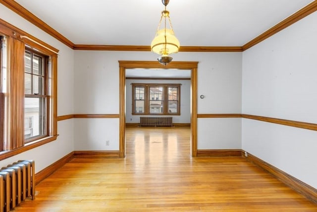 unfurnished dining area featuring crown molding, radiator heating unit, and light wood-type flooring