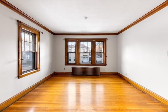 spare room featuring radiator, crown molding, light hardwood / wood-style flooring, and plenty of natural light