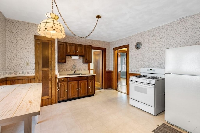 kitchen featuring sink, pendant lighting, and white appliances