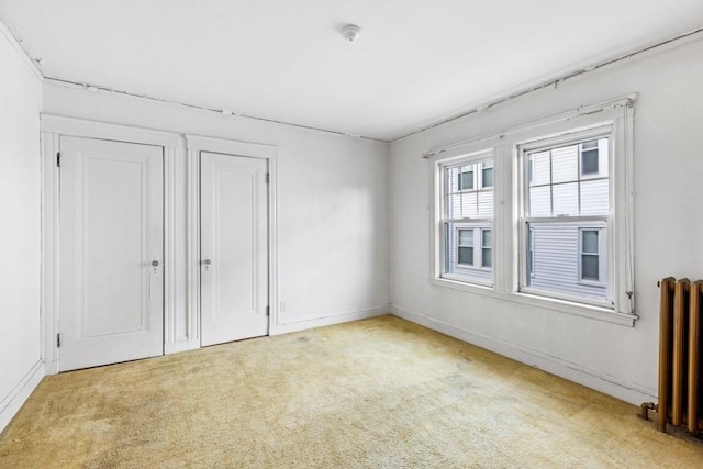 empty room featuring radiator and light colored carpet