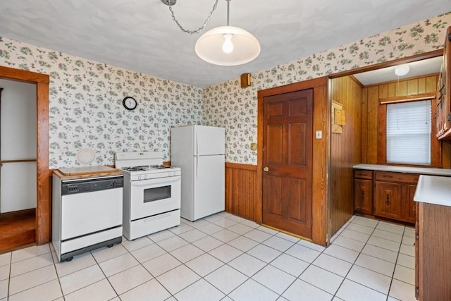 kitchen with light tile patterned flooring, white appliances, and hanging light fixtures