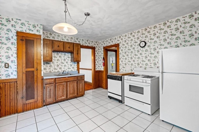 kitchen with hanging light fixtures, light tile patterned flooring, sink, and white appliances