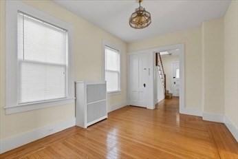 empty room with a chandelier, baseboards, and wood finished floors