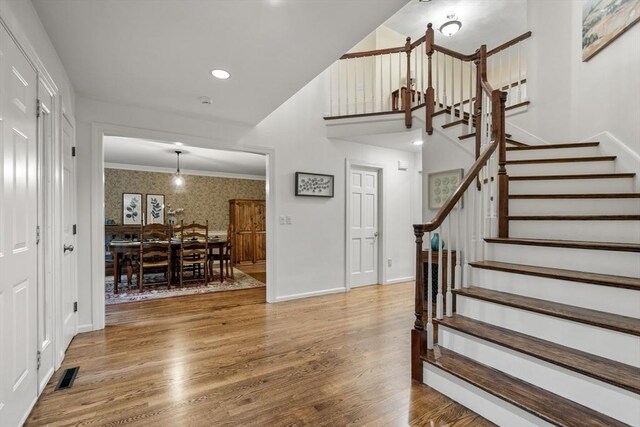27 Bowker Dr, Sudbury, MA 01776 - foyer entrance featuring wallpapered walls, stairway, wood finished floors, baseboards, and ornamental molding