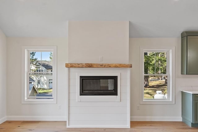 unfurnished living room with baseboards, a wealth of natural light, and light wood-style floors