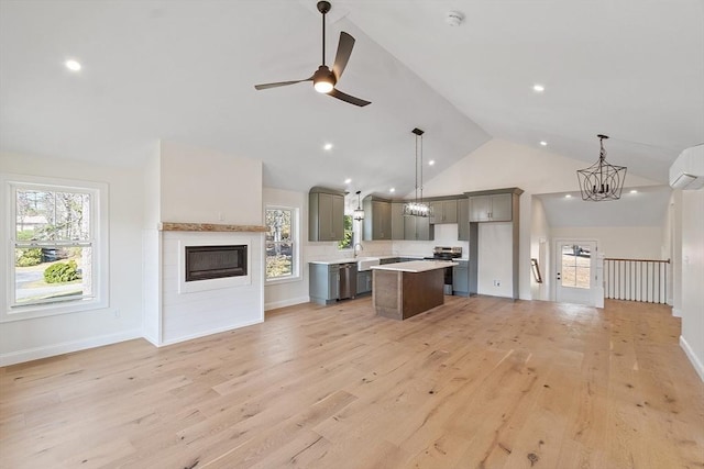 kitchen with ceiling fan with notable chandelier, open floor plan, a wall unit AC, gray cabinetry, and appliances with stainless steel finishes