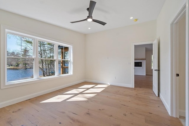 empty room with baseboards, light wood-type flooring, a ceiling fan, and recessed lighting