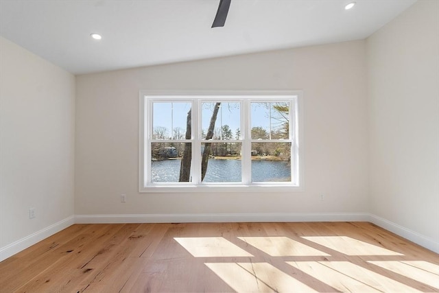 unfurnished room featuring light wood-type flooring, recessed lighting, ceiling fan, a water view, and baseboards