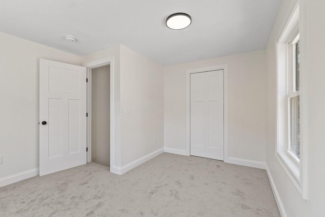 unfurnished bedroom featuring baseboards, light carpet, and a closet