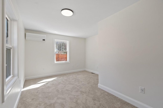 spare room with carpet flooring, baseboards, and a wall unit AC
