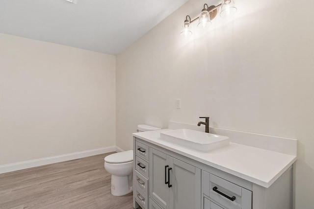 bathroom with vanity, toilet, baseboards, and wood finished floors