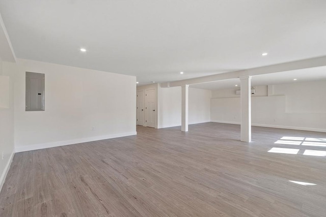 finished basement with baseboards, recessed lighting, light wood-type flooring, and electric panel