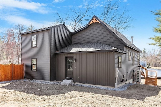 back of house featuring fence and a shingled roof