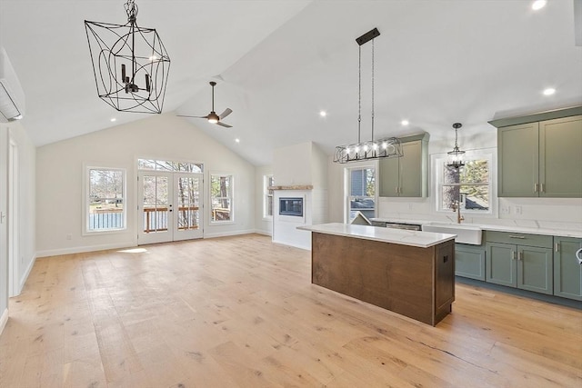 kitchen with a sink, ceiling fan with notable chandelier, green cabinetry, decorative light fixtures, and a center island