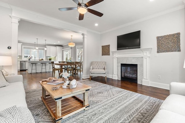 living room with ceiling fan, dark wood-type flooring, a premium fireplace, and ornamental molding