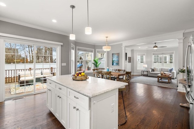 kitchen with ceiling fan, a center island, pendant lighting, white cabinets, and decorative columns