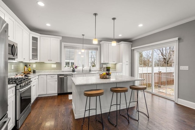 kitchen with stainless steel appliances, white cabinetry, hanging light fixtures, and a center island