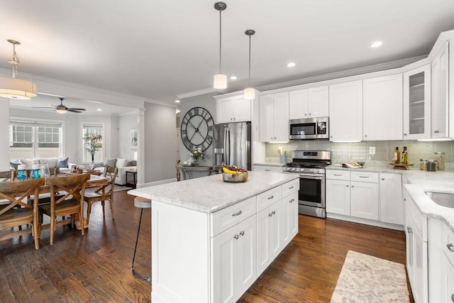 kitchen with hanging light fixtures, appliances with stainless steel finishes, white cabinetry, and a kitchen island