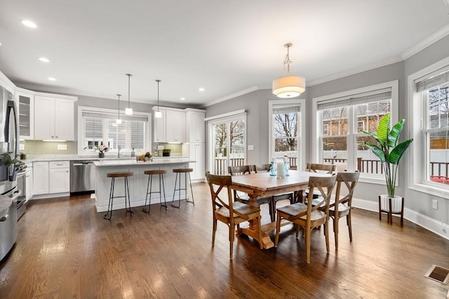 dining space featuring crown molding, a healthy amount of sunlight, and dark hardwood / wood-style floors