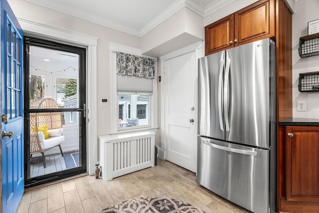 kitchen with crown molding, freestanding refrigerator, brown cabinetry, light wood-type flooring, and radiator heating unit