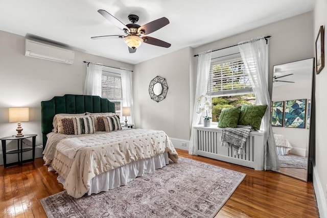 bedroom featuring baseboard heating, hardwood / wood-style floors, baseboards, and an AC wall unit
