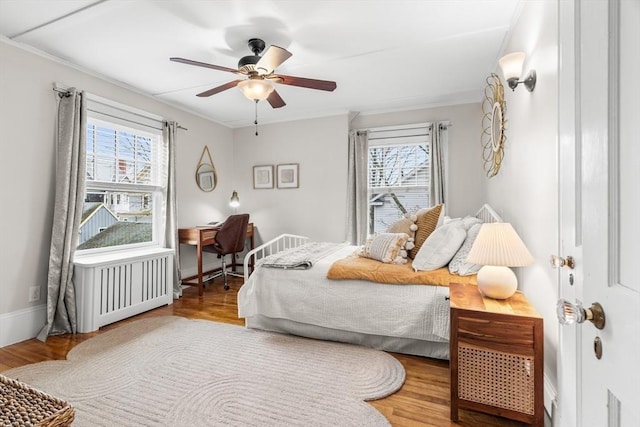 bedroom featuring crown molding, a ceiling fan, radiator, and wood finished floors
