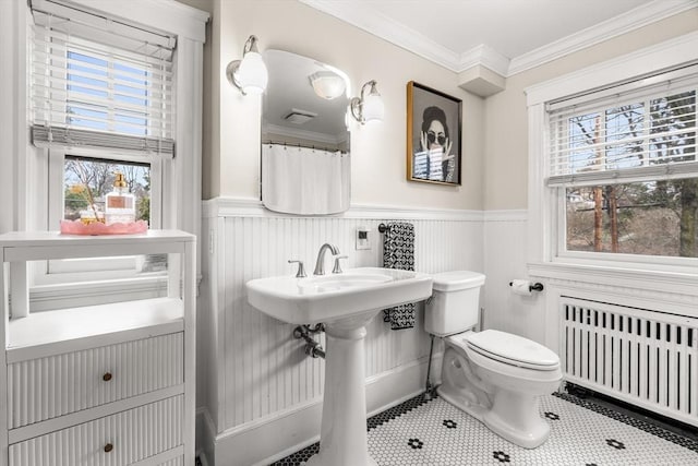 full bath featuring toilet, crown molding, radiator heating unit, and a wainscoted wall