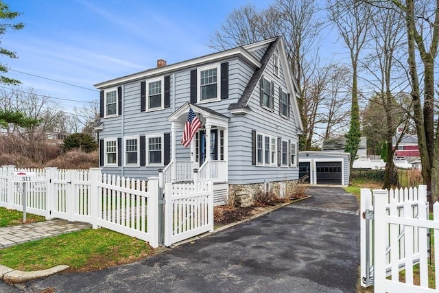 view of front of home with a garage, a chimney, an outbuilding, and a fenced front yard