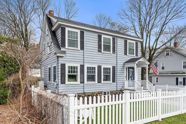 view of front of house with roof with shingles, a chimney, and a fenced front yard