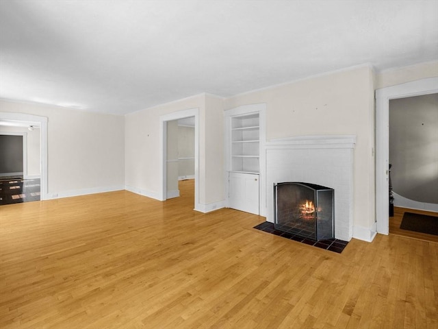14 Parkman St, Westborough, MA 01581 - unfurnished living room featuring a fireplace with flush hearth, light wood-type flooring, baseboards, and built in shelves