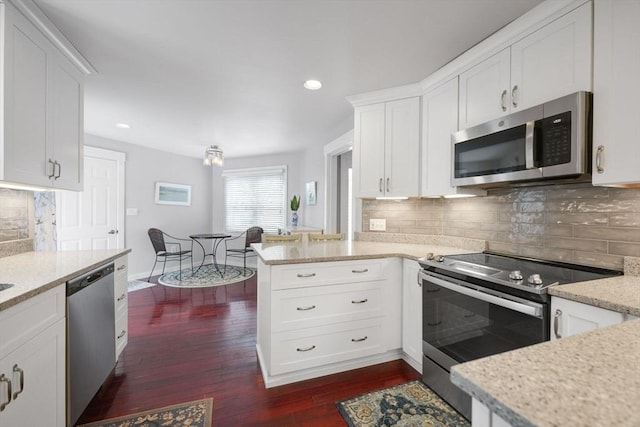 kitchen featuring appliances with stainless steel finishes, backsplash, light stone countertops, white cabinets, and kitchen peninsula