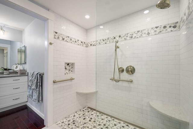 bathroom with hardwood / wood-style flooring, tiled shower, and vanity