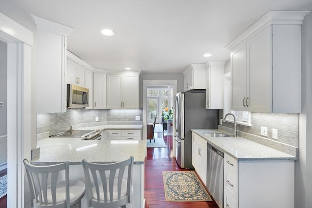 kitchen with sink, white cabinetry, a kitchen breakfast bar, kitchen peninsula, and stainless steel appliances