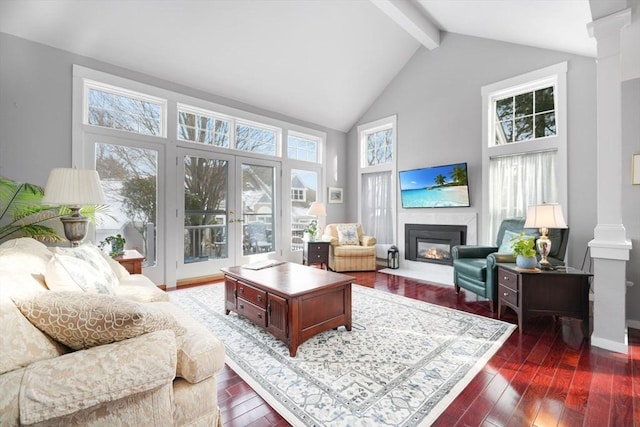 living room featuring dark wood-type flooring, decorative columns, beamed ceiling, and a high ceiling