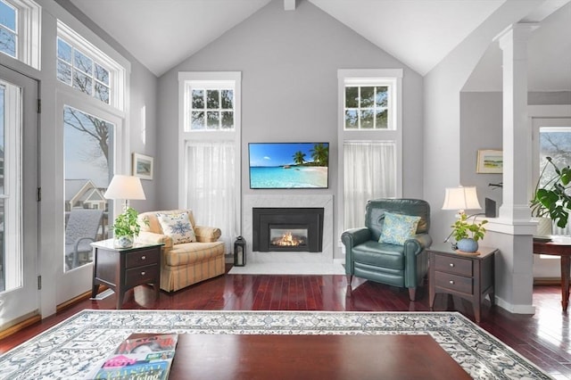 living area featuring high vaulted ceiling, dark hardwood / wood-style flooring, and decorative columns