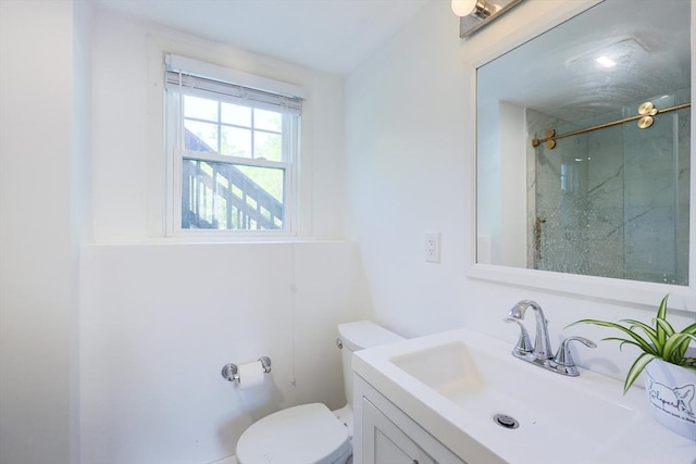 bathroom featuring toilet, vanity, and a shower