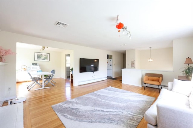 living room with light wood-style flooring and baseboard heating