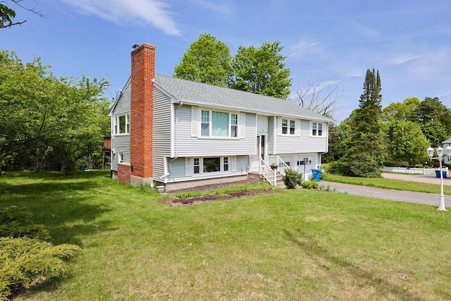 bi-level home with a chimney, a garage, a front lawn, and driveway